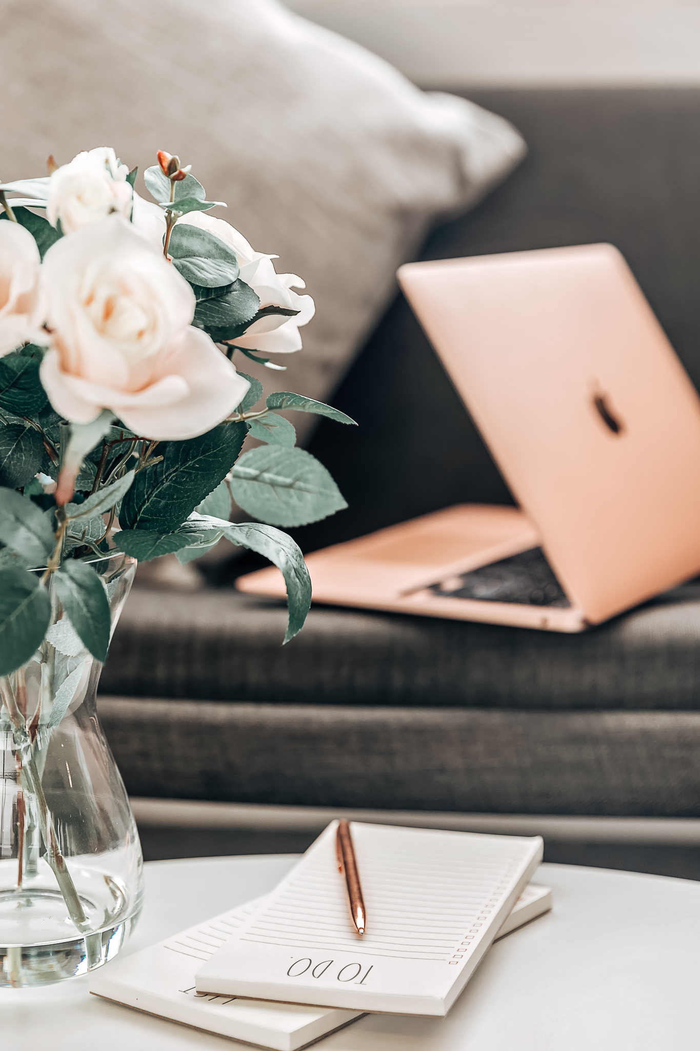 coffee-table-flowers-notepad-pen-sofa-open-laptop